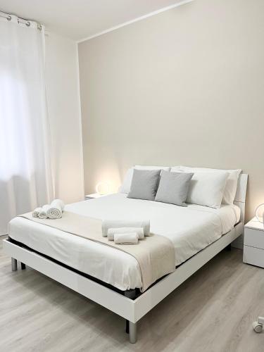 a white bedroom with a large bed with white sheets at G&L airport apartment in BGY in Orio al Serio