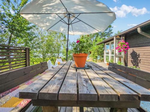 une table en bois avec un parasol sur une terrasse dans l'établissement Holiday Home Kottage by Interhome, à Littoinen