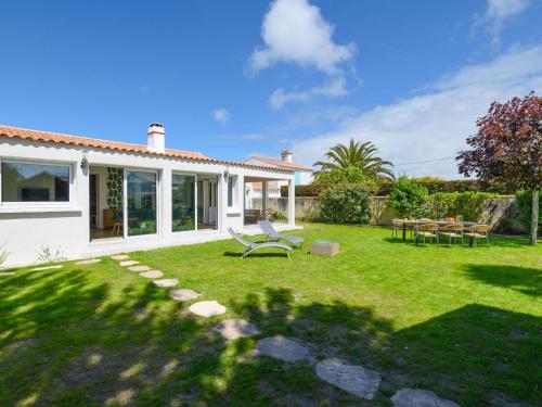 a white house with a yard with a chair at Holiday Home Casa Nostress-Villa 6 pers by Interhome in Noirmoutier-en-l'lle