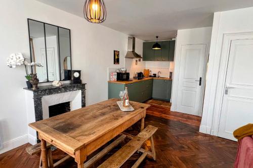 une cuisine avec une table en bois et une cheminée dans l'établissement Appartement L’Éclat du Colza, à Mortagne-au-Perche