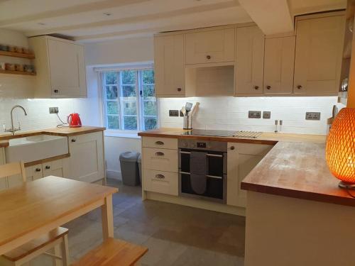 a kitchen with white cabinets and a stove top oven at River cottage Dartmoor in Holne