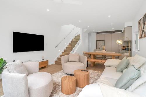 a living room with white furniture and a tv at Tranquil Haven in Balmain in Sydney