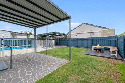 a patio with a fire pit and a fence at Wine Down Retreat - The Great Entertainer with Heated Pool, Fireplace and Firepit for the Perfect All-Season Escape in Cessnock