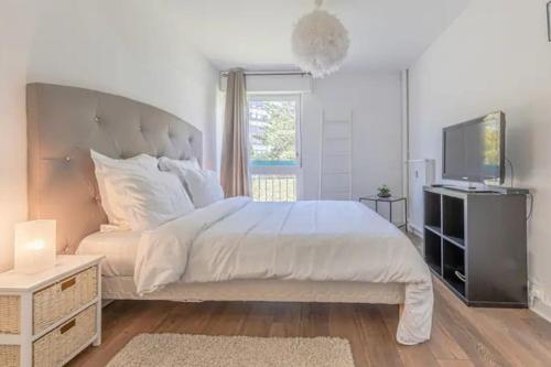a white bedroom with a large bed and a television at Le Pompidou 3 pièces à 2 min de la gare in Metz