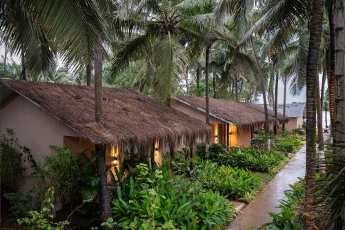 a resort with a thatched roof and palm trees at Palma Beach Resort in Mandrem