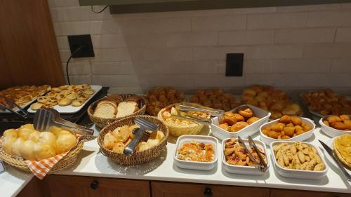 a buffet filled with different types of bread and pastries at Hotel das Palmeiras in Paracatu