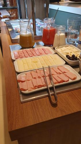 a counter with several different types of meats and cheese at Hotel das Palmeiras in Paracatu