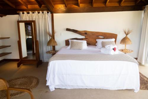 a bedroom with a large bed with white sheets at Pousada Vila do Mar in Caraíva
