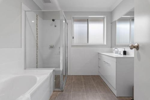 a white bathroom with a tub and a shower at Hunter Explorer - Games Room & Outdoor Spa in Cessnock