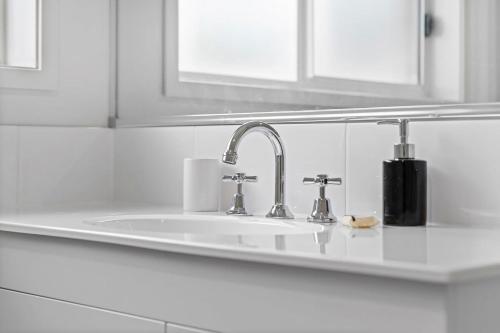 a white kitchen counter with a sink and two faucets at Hunter Explorer - Games Room & Outdoor Spa in Cessnock