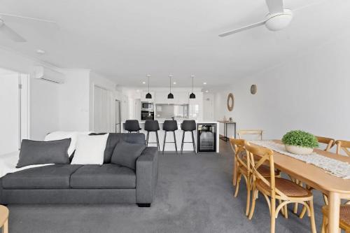 a living room with a couch and a table at Seashells Sweet Retreat 450m walk to CBD in Nelson Bay