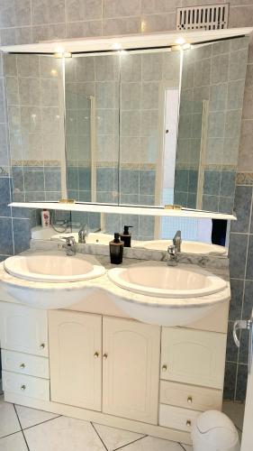 une salle de bain avec deux lavabos et un grand miroir dans l'établissement La Couregant House vue mer, à Ploemeur