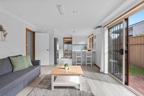 a living room with a couch and a table at Shoreline Retreat 900m to the beach in Fingal Bay