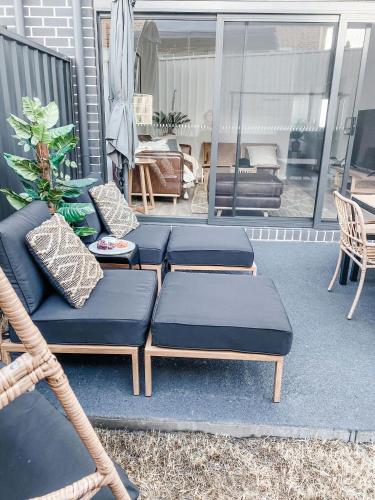 a patio with three blue cushioned chairs on a porch at Ocean View Townhouse in Dunmore