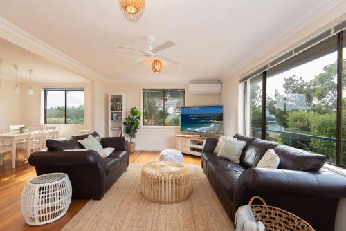 a living room with leather couches and a flat screen tv at Ocean Views Walk to Malua Beach EV & Pet Friendly in Malua Bay