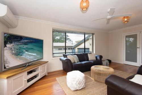 a living room with a large flat screen tv at Ocean Views Walk to Malua Beach EV & Pet Friendly in Malua Bay