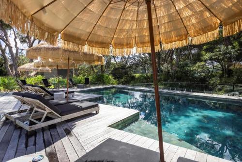 a swimming pool with two chairs and an umbrella at Privately Managed Villa 12 Bangalay Luxury Villas in Shoalhaven Heads