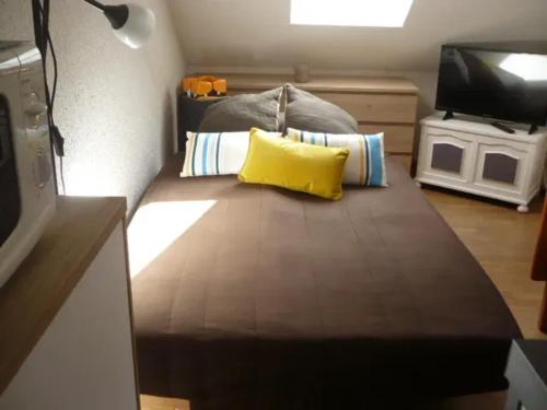 Cette petite chambre comprend un lit avec un oreiller jaune. dans l'établissement Studio douillet à Puy-Saint-Vincent, 16 m², vue sur la montagne., à Puy-Saint-Vincent