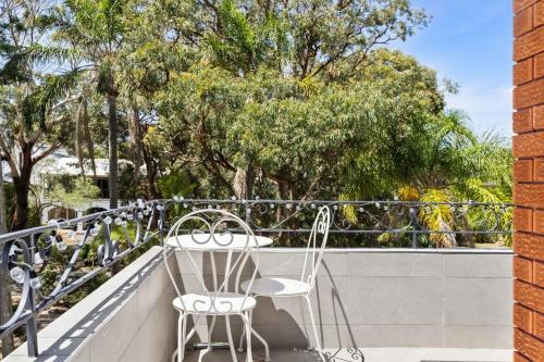 two chairs sitting on a balcony with trees at The Nest Luxury Apartment 100m to the Beach in Shoal Bay