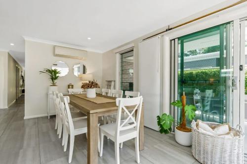 a dining room with a wooden table and chairs at Oscar's Broulee Beach Luxury Coastal Living in Broulee