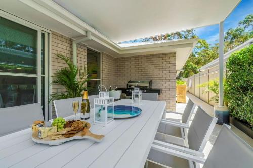 ein weißer Tisch und Stühle auf einer Terrasse in der Unterkunft Oscar's Broulee Beach Luxury Coastal Living in Broulee