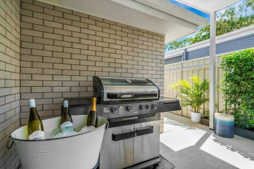 ein Grill mit Weinflaschen in einem Eimer auf einer Terrasse in der Unterkunft Oscar's Broulee Beach Luxury Coastal Living in Broulee