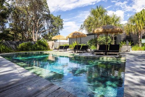 a swimming pool with chairs and umbrellas at Privately Managed Villa 13 Bangalay Luxury Villas in Shoalhaven Heads