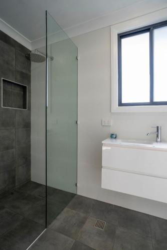 a bathroom with a glass shower and a sink at Rosa Beach Studio Getaway in Vincentia