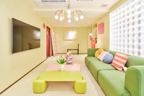 a living room with a green couch and a coffee table at 寅ホテル 御徒町 TORA HOTEL Okachimachi in Tokyo
