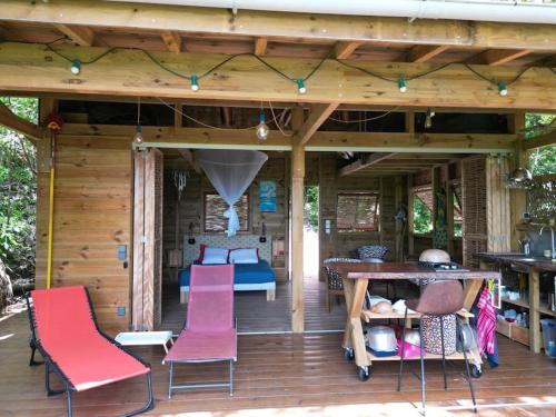 a wooden deck with pink chairs and a table at cabane entre les arbres in Deshaies