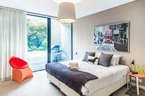 a bedroom with a large bed and a red chair at Leafy Inner City Apartment Camperdown in Sydney