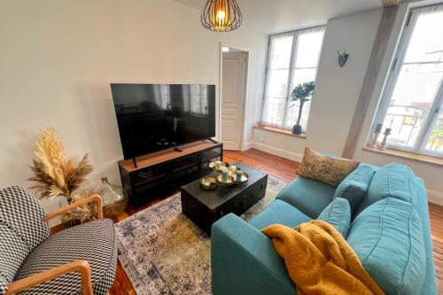 un salon avec un canapé bleu et une télévision à écran plat dans l'établissement Appartement Le Chant du Blé, à Mortagne-au-Perche
