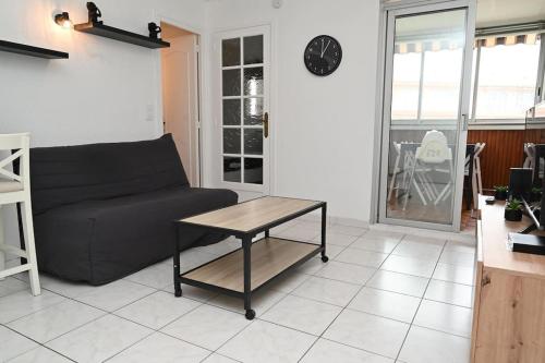 un salon avec un canapé noir et une table dans l'établissement Charmant studio cabine avec parking, à Fréjus