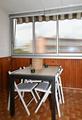 une table et des chaises dans une pièce avec une fenêtre dans l'établissement Charmant studio cabine avec parking, à Fréjus