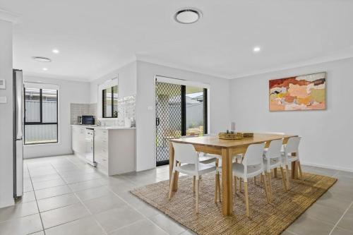 a kitchen and dining room with a wooden table and chairs at Time Out Beautifully decorated new home in Cessnock