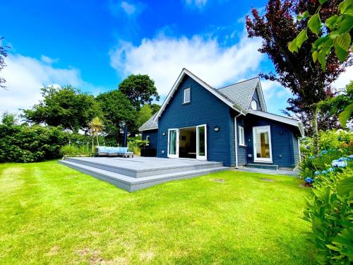 a blue house with a large yard at Trewhiddle Retreat V9 by Together Travel - Luxury 4-Bedroom Villa in St Austell