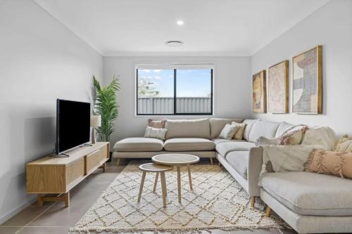 a living room with a couch and a tv at Time Out Beautifully decorated new home in Cessnock