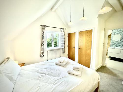 a bedroom with a white bed with two towels on it at Trewhiddle Retreat V9 by Together Travel - Luxury 4-Bedroom Villa in St Austell