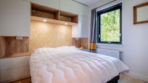 ein Schlafzimmer mit einem großen weißen Bett mit einem Fenster in der Unterkunft Bungalows Papillon Country Resort in Denekamp