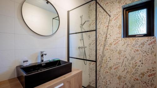ein Badezimmer mit Waschbecken und Spiegel in der Unterkunft Bungalows Papillon Country Resort in Denekamp
