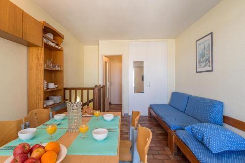 a living room with a table and a blue couch at Résidence Pierre et Vacances Le Port in Hyères