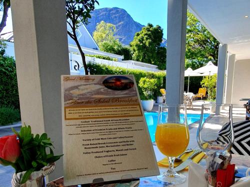 a table with a menu and a glass of wine at Fleur du Soleil Luxury Guesthouse in Franschhoek