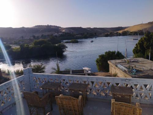 a balcony with tables and chairs and a river at Nubian Life Nile View in Aswan