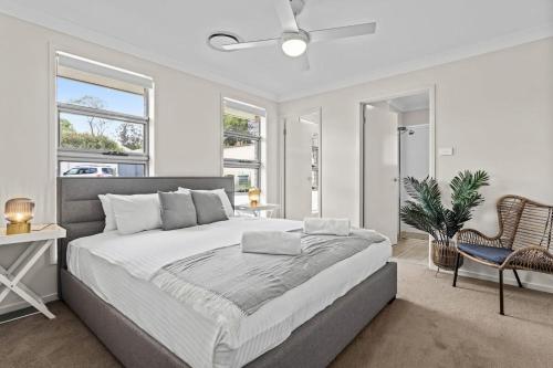 a white bedroom with a large bed and windows at Wine Country Cottage Stylish Family Getaway in Cessnock