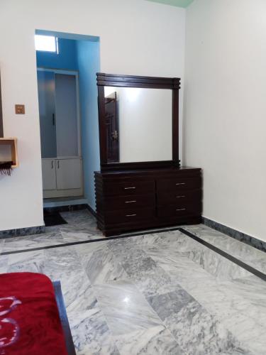 a bedroom with a large mirror and a dresser at Hotel Red Roof & Restaurant in Abbottābād