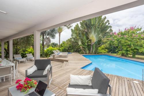 a patio with a pool and chairs and a table at KaruHuapi in Le Gosier