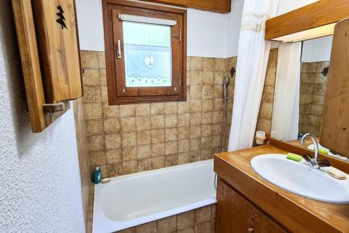 La salle de bains est pourvue d'un lavabo, d'une baignoire et d'une fenêtre. dans l'établissement Exceptional view of village and mountain, à Megève