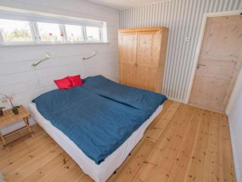 a bedroom with a bed with blue sheets and red pillows at Luxury Lodge with Limfjord View - By Traum Ferienwohnungen in Spottrup