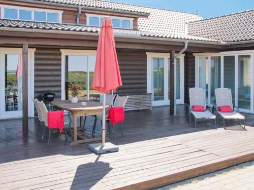 a wooden deck with a table and chairs and an umbrella at Luxury Lodge with Limfjord View - By Traum Ferienwohnungen in Spottrup