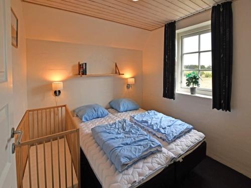 a bedroom with a bed with blue pillows and a window at Luxury Retreat by the Sea - By Traum Ferienwohnungen in Ulfborg